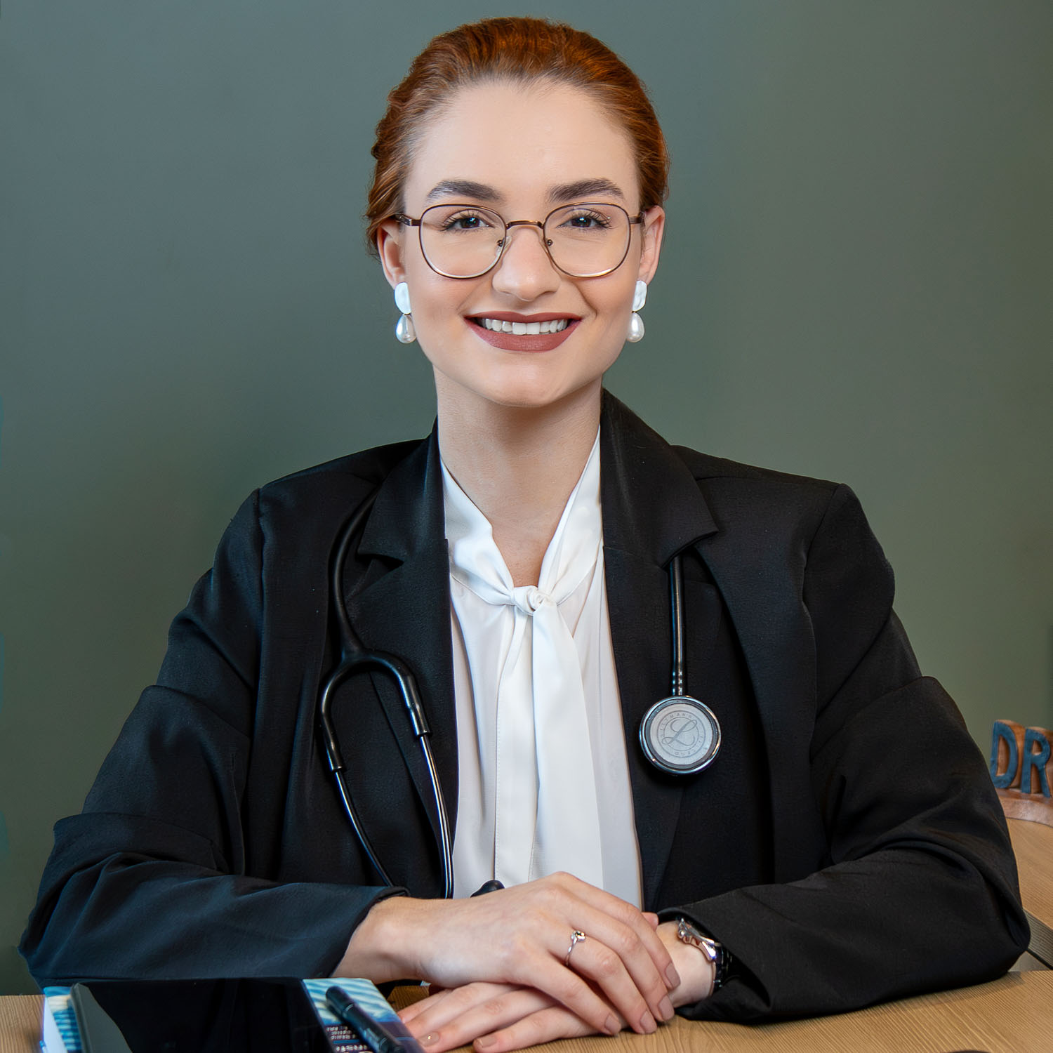 Dra Vitória Cuida, médica de família e paliativista em Juiz de Fora, em retrato profissional com estetoscópio, simbolizando confiança e cuidado humanizado.